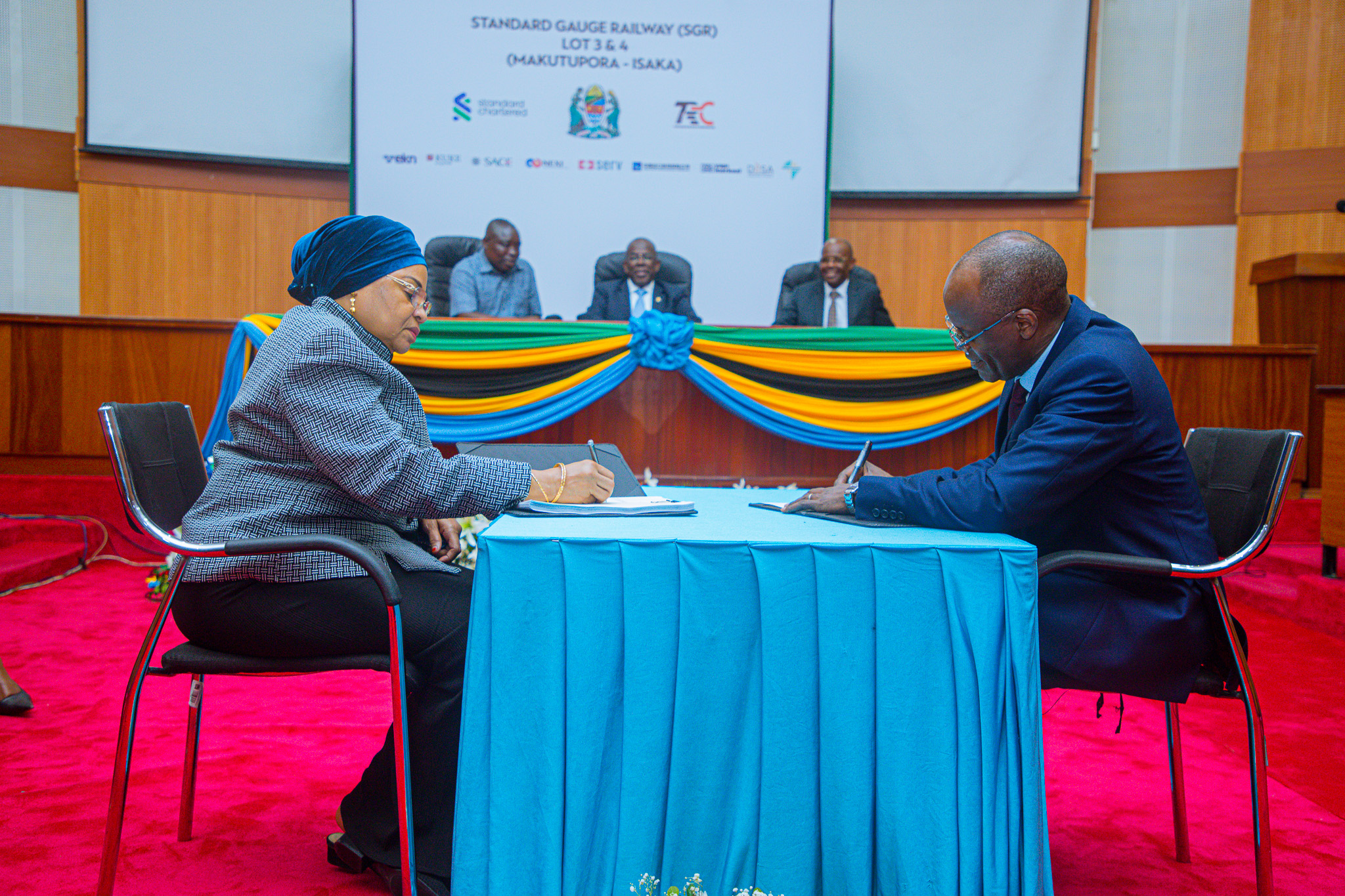 Katibu Mkuu Wizara ya Fedha na Mlipaji Mkuu wa Serikali, Dkt. Natu El-maamry Mwamba na Afisa Mtendaji Mkuu wa Benki ya Standard Chartered, Bw. Herman Kasekende, wakisaini Mkataba wa kugharamia ukamilishaji wa Reli ya Kisasa (Standard Gauge -SGR), kipande cha tatu (loti 3) na cha nne (loti 4) kutoka Makutupora ya mkoani Singida hadi Isaka, yenye thamani ya takriban dola za Marekani bilioni 1.277, katika hafla iliyofanyika katika Ukumbi wa Mikutano wa Kambarage, Treasury Square, jijini Dodoma.